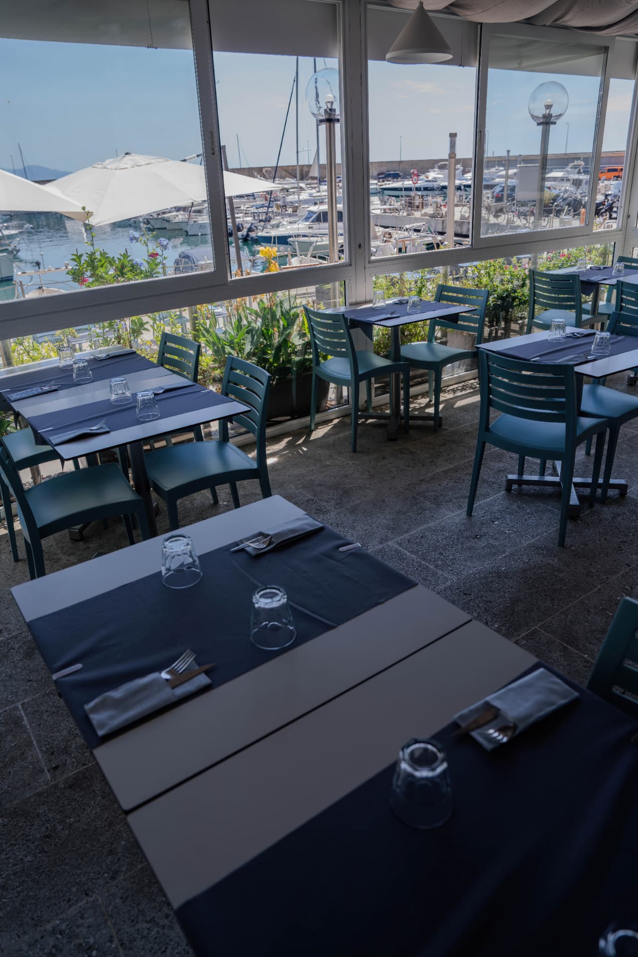 Sala di Q.be Bistrot con vetrate affacciate sul porto turistico di Arenzano